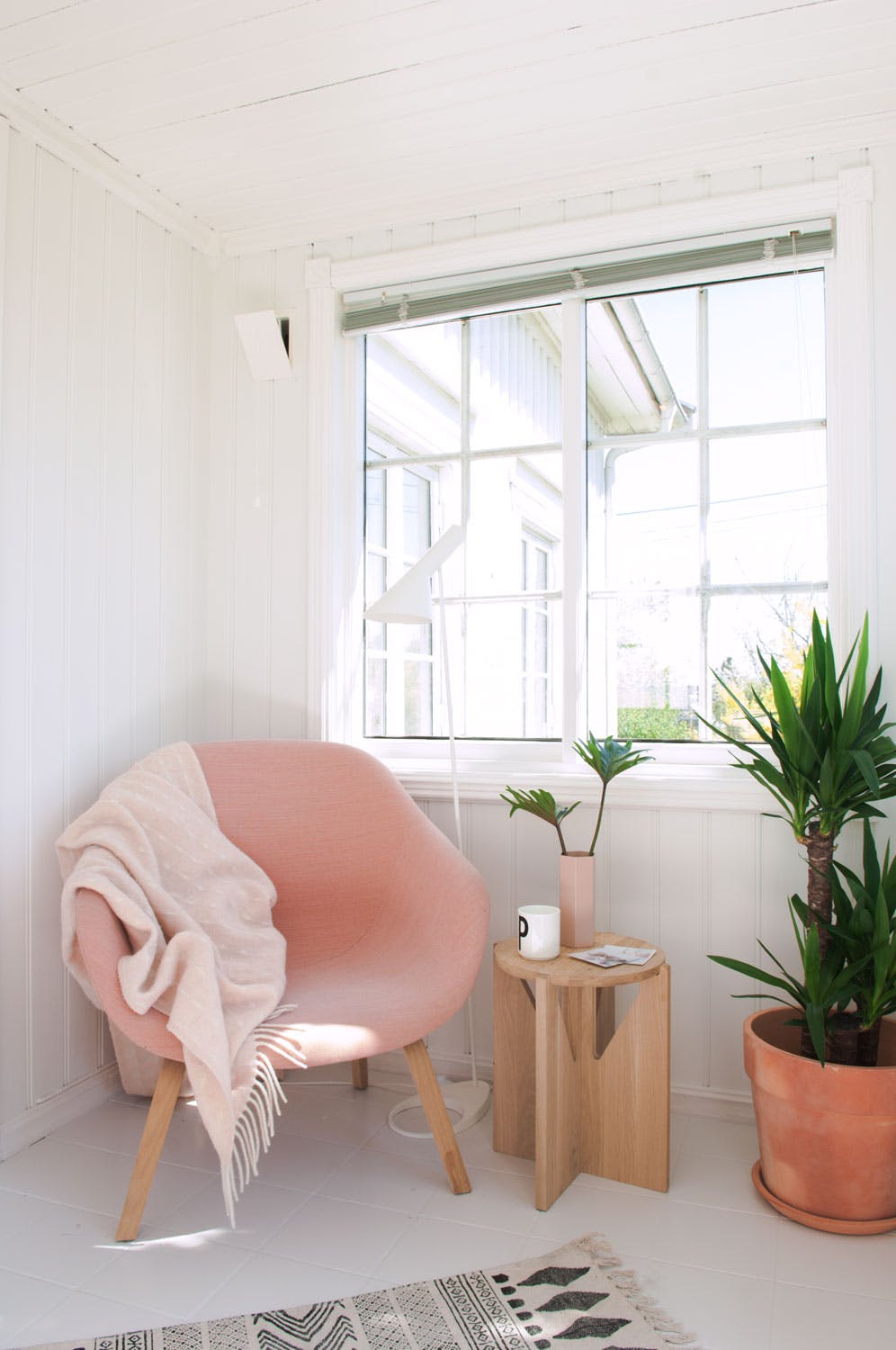 Vakker vinterhage i den lyse, lekre vinterhagen står en rosa stol fra Hay. Sidebordet i tre er fra Kristina Dam Studio og leselampen AJ Floor er fra Louis Poulsen. Blomsterpotten i terrakotta er fra Plantasjen.